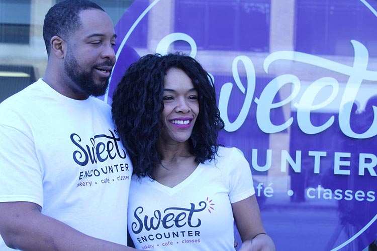 two people wearing Sweet Encounter t-shirts standing in front of the Sweet Encounter location